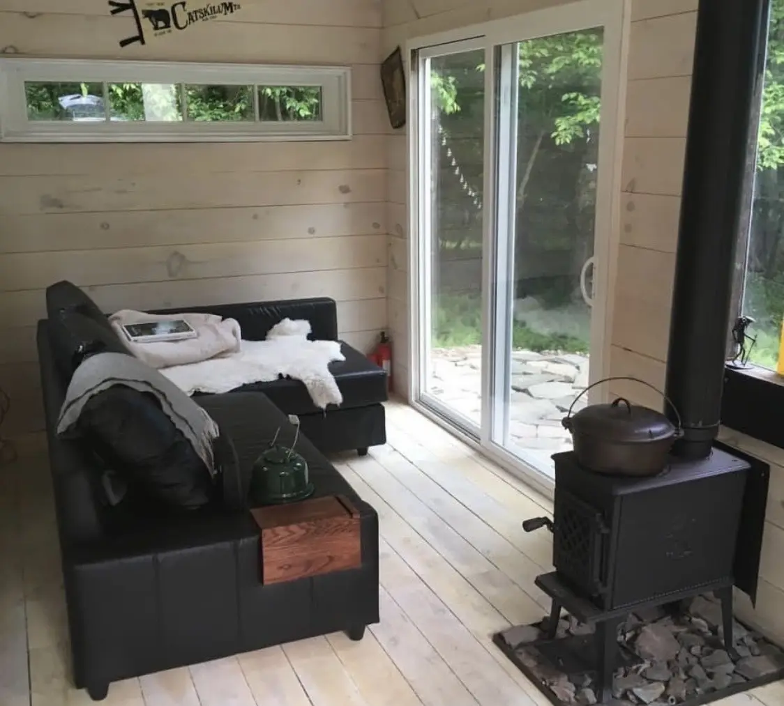 Tiny home living area with wood stove and sliding glass doors