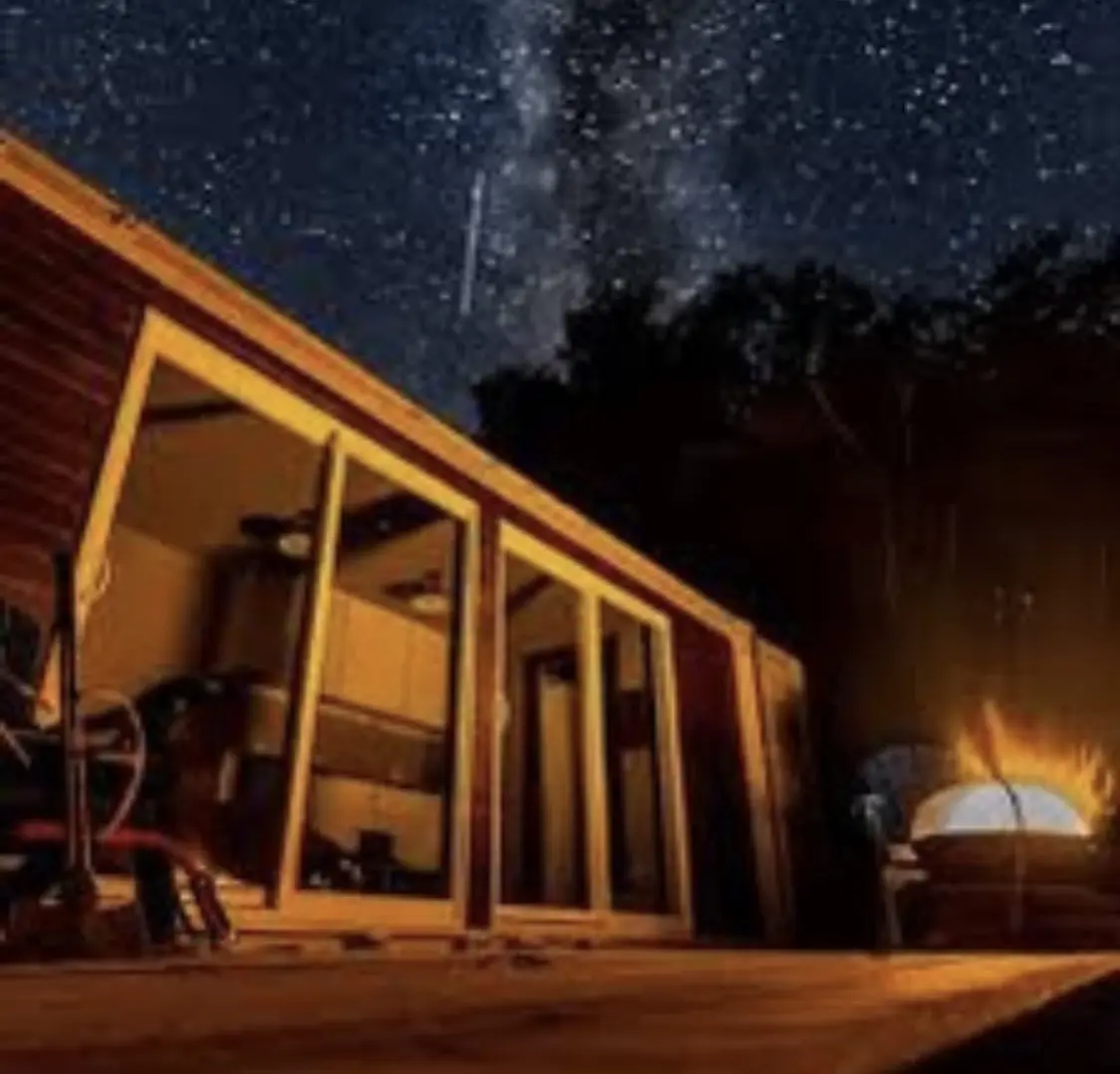 Off-grid tiny home under a starry night sky with a campfire — The Foothills Tiny Home Company