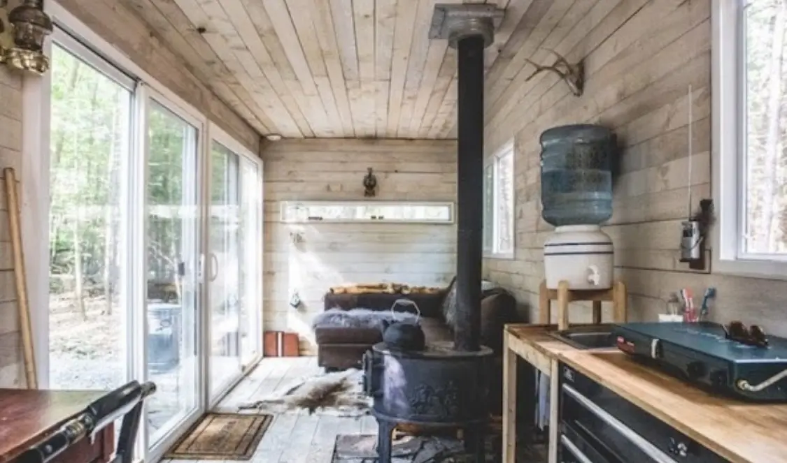 Off-grid tiny home interior with wood stove and water system